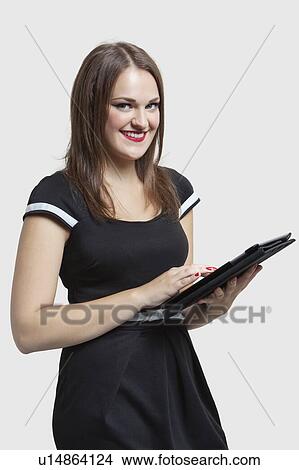 Picture - Portrait of young woman using tablet PC over gray background. Fotosearch
