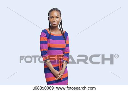 Stock Photo - Portrait of young woman wearing striped dress against light blue background. Fotosearch