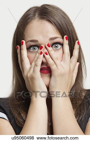 Stock Photo - Portrait of young woman with gray eyes and red painted nails over gray background. Fotosearch