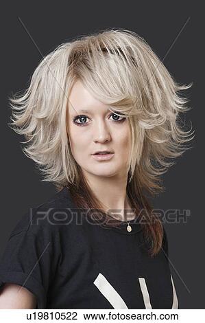 Stock Image - Portrait of young woman with modern hairstyle over black background. Fotosearch