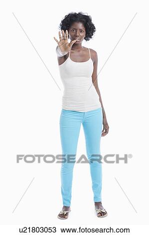 Stock Image - Portrait of young woman with stop gesture standing over white background. Fotosearch