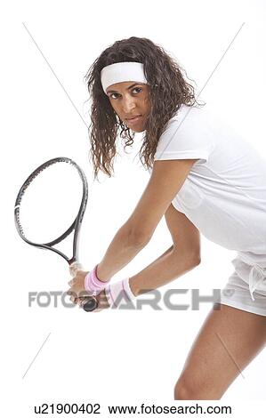 Stock Image - Portrait of young woman with tennis racket against white background. Fotosearch