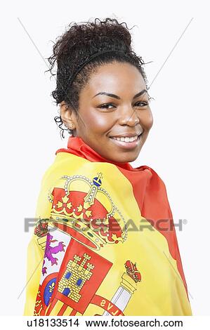 Picture - Portrait of young woman wrapped in Spanish flag over white background. Fotosearch