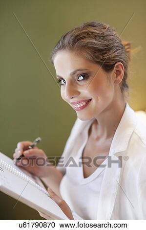 Portrait of young woman writing notes on spiral notebook View Large Photo Image Stock Image - Portrait of young woman writing notes on spiral notebook. Fotosearch