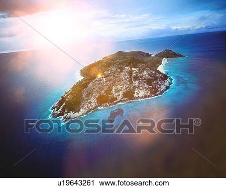 Stock Image - Private island in the ocean with sun shining. Fotosearch