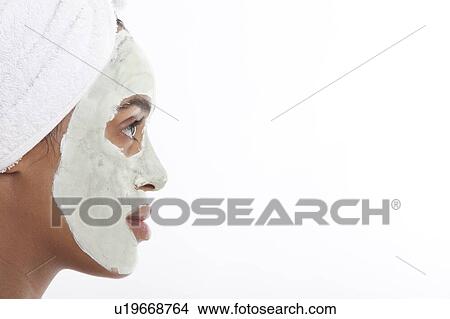 Picture - Profile shot of young Mixed Race woman with face pack against white background. Fotosearch