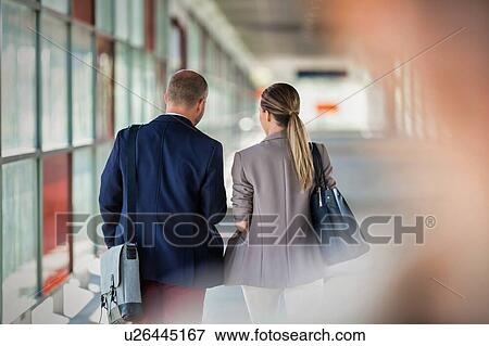 Stock Photo - Rear view of businessman and businesswoman walking and talking. Fotosearch