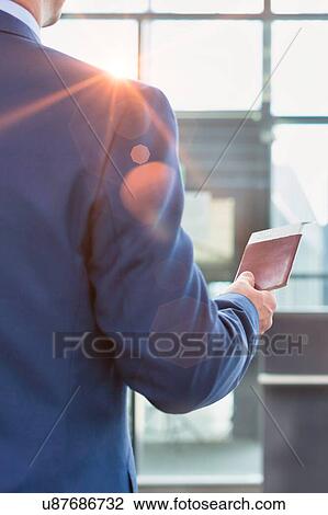 Rear view of mature businessman holding his passport and boarding pass at airport View Large Photo Image Stock Image - Rear view of mature businessman holding his passport and boarding pass at airport. Fotosearch