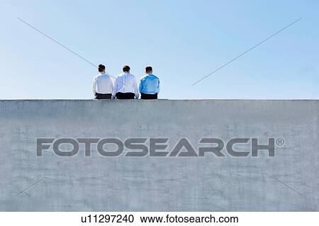 Rear view of mature thoughtful businessmen sitting on office rooftop View Large Photo Image Stock Image - Rear view of mature thoughtful businessmen sitting on office rooftop. Fotosearch