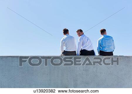 Rear view of mature thoughtful businessmen sitting on office rooftop View Large Photo Image Stock Image - Rear view of mature thoughtful businessmen sitting on office rooftop. Fotosearch
