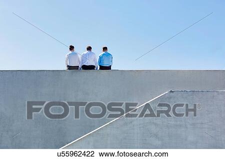 Rear view of mature thoughtful businessmen sitting on office rooftop View Large Photo Image Stock Image - Rear view of mature thoughtful businessmen sitting on office rooftop. Fotosearch