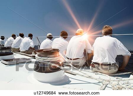 Picture - Rear view of sailing crew with lens flare. Fotosearch