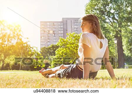 Rear view of young attractive businesswoman sitting on the grass while watching the sunset View Large Photo Image Stock Photo - Rear view of young attractive businesswoman sitting on the grass while watching the sunset. Fotosearch
