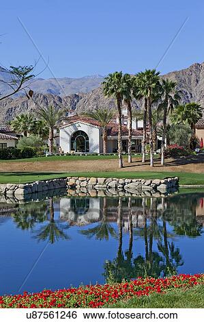 Stock Photograph - Reflection of villa in water with mountains in background. Fotosearch