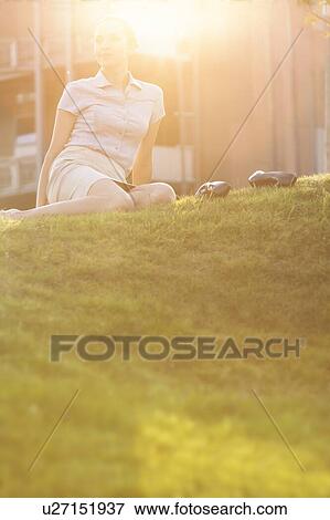 Relaxed young businesswoman sitting in office lawn View Large Photo Image Stock Photo - Relaxed young businesswoman sitting in office lawn. Fotosearch