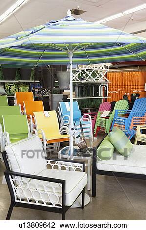 Stock Image - Seating furniture and patio umbrella for sale in garden furniture store. Fotosearch
