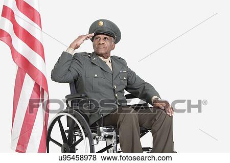 Senior male US military officer in wheelchair saluting American flag over gray background View Large Photo Image Stock Photo - Senior male US military officer in wheelchair saluting American flag over gray background. Fotosearch