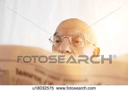 Stock Photography - Senior Man reading his financial newspaper with sunshine. Fotosearch