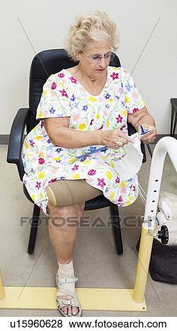 Stock Photo - Senior woman with top half of prosthetic leg knitting. Fotosearch