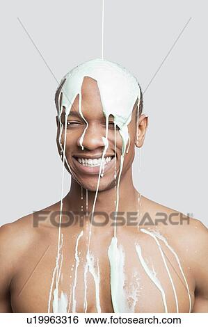 Shirtless young man with paint falling on his head against gray background View Large Photo Image Stock Photograph - Shirtless young man with paint falling on his head against gray background. Fotosearch