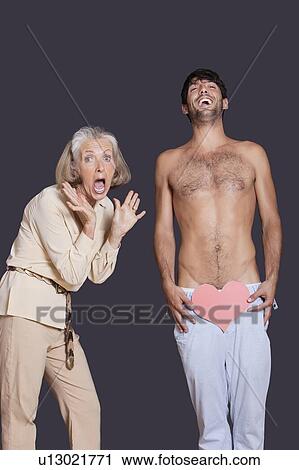 Shocked senior woman with young man holding red paper heart against black background View Large Photo Image Stock Image - Shocked senior woman with young man holding red paper heart against black background. Fotosearch