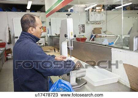 Stock Image - Side view of male employee working in supermarket. Fotosearch