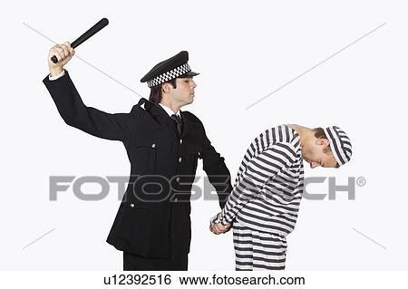 Side view of police officer with nightstick arresting male prisoner against gray background View Large Photo Image Stock Photograph - Side view of police officer with nightstick arresting male prisoner against gray background. Fotosearch