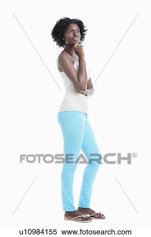 Stock Photography - Side view of thoughtful young woman standing over white background. Fotosearch