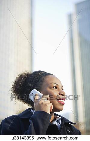 Stock Photography - Smiling African American young woman using mobile phone. Fotosearch