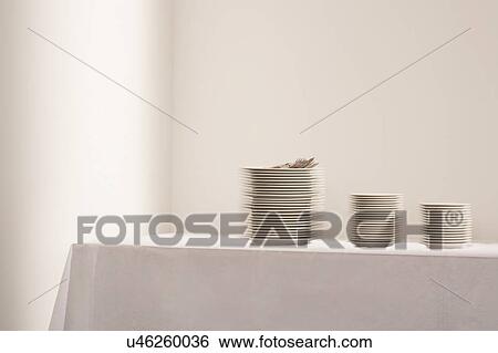Stock Photograph - Stacks of plates and cutlery on table. Fotosearch