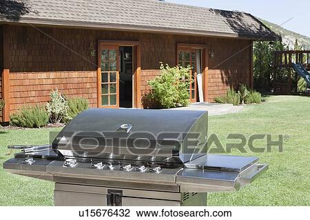 Stock Image - Stainless steel barbecue grill in front of house at lawn. Fotosearch