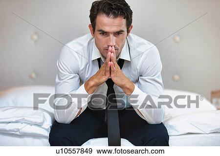 Stressed and overworked businessman sitting on the bed View Large Photo Image Stock Photo - Stressed and overworked businessman sitting on the bed. Fotosearch
