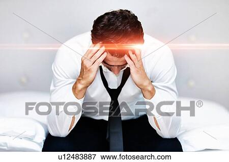 Stressed and overworked businessman sitting on the bed View Large Photo Image Stock Photo - Stressed and overworked businessman sitting on the bed. Fotosearch