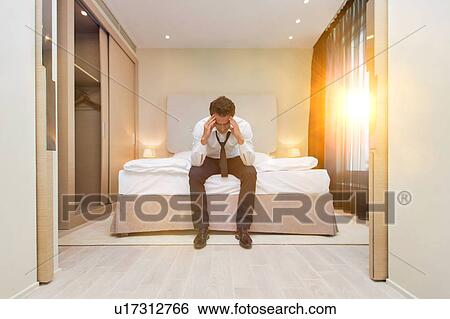 Stressed and overworked businessman sitting on the bed View Large Photo Image Stock Photograph - Stressed and overworked businessman sitting on the bed. Fotosearch