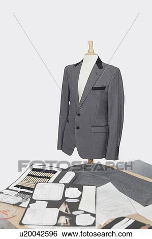 Stock Photograph - Suit on tailor's dummy with design layouts over gray background. Fotosearch