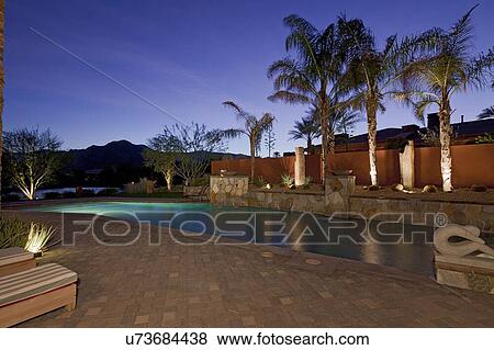 Swimming pool under lights in evening of luxury mansion View Large Photo Image Stock Photo - Swimming pool under lights in evening of luxury mansion. Fotosearch