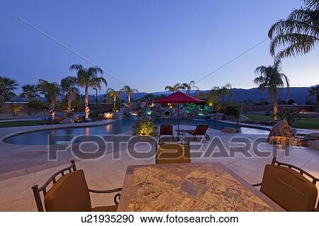 Swimming pool with chaise lounge outside mansion at dusk View Large Photo Image Stock Image - Swimming pool with chaise lounge outside mansion at dusk. Fotosearch