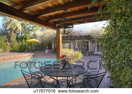 Stock Photograph - Table and chair at poolside in mansion. Fotosearch