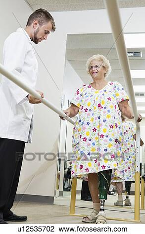 Stock Image - Technician looking at senior woman having ambulatory therapy. Fotosearch