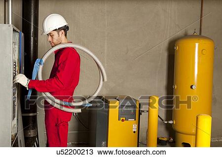 Stock Image - Technician operating heavy duty machinery in manufacturing plant. Fotosearch