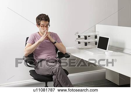 Stock Photo - Thoughtful young businessman sitting on office chair. Fotosearch