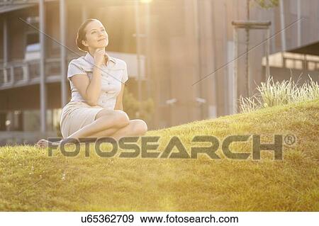 Thoughtful young businesswoman relaxing in office lawn View Large Photo Image Stock Photo - Thoughtful young businesswoman relaxing in office lawn. Fotosearch