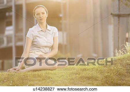Thoughtful young businesswoman sitting on office lawn View Large Photo Image Stock Photo - Thoughtful young businesswoman sitting on office lawn. Fotosearch