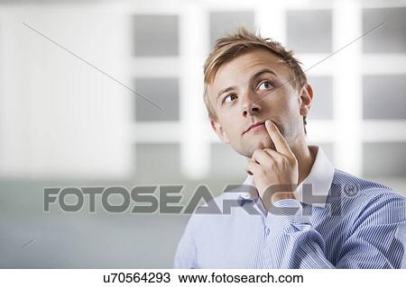 Thoughtful young Caucasian businessman at office View Large Photo Image Stock Image - Thoughtful young Caucasian businessman at office. Fotosearch