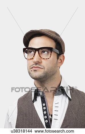 Picture - Thoughtful young Caucasian man in flat cap against white background. Fotosearch