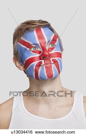 Stock Photograph - Thoughtful young Caucasian man with British flag painted on face against white background. Fotosearch
