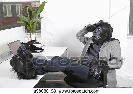 Stock Photo - Thoughtful young man in gorilla costume resting at office. Fotosearch