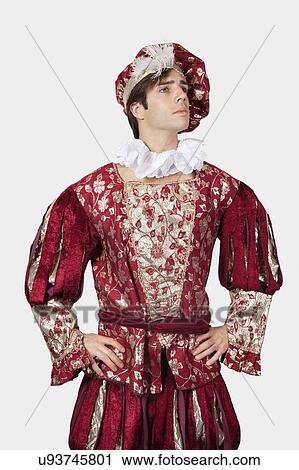 Thoughtful young man in old-fashioned costume with hands on hips against gray background View Large Photo Image Stock Image - Thoughtful young man in old-fashioned costume with hands on hips against gray background. Fotosearch