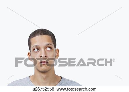 Thoughtful young mixed race man looking sideways against white background View Large Photo Image Stock Photo - Thoughtful young mixed race man looking sideways against white background. Fotosearch
