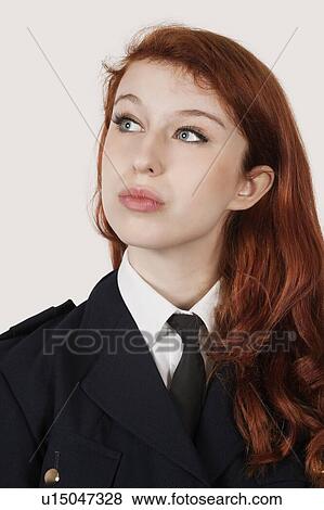 Stock Photo - Thoughtful young woman in police officer's costume against gray background. Fotosearch